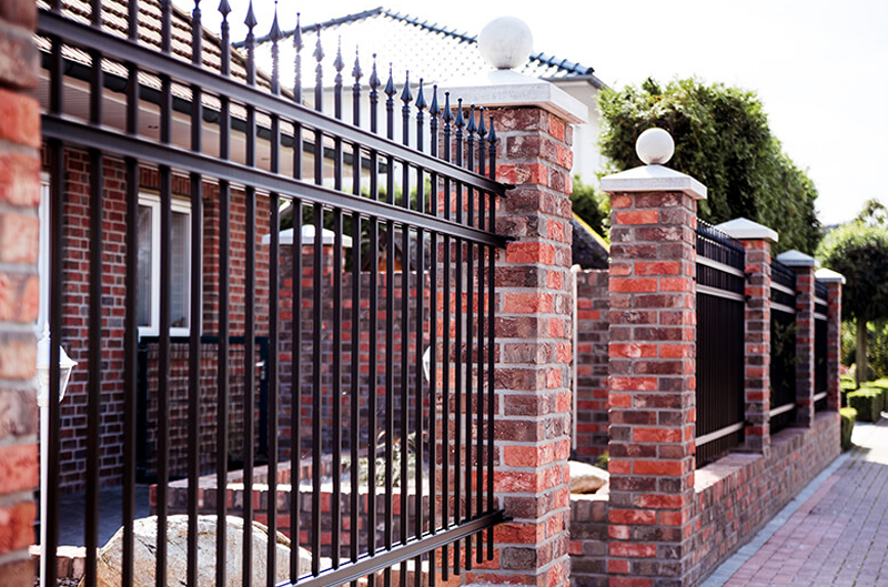 Metallzaun vor einem Haus mit rotem Klinker