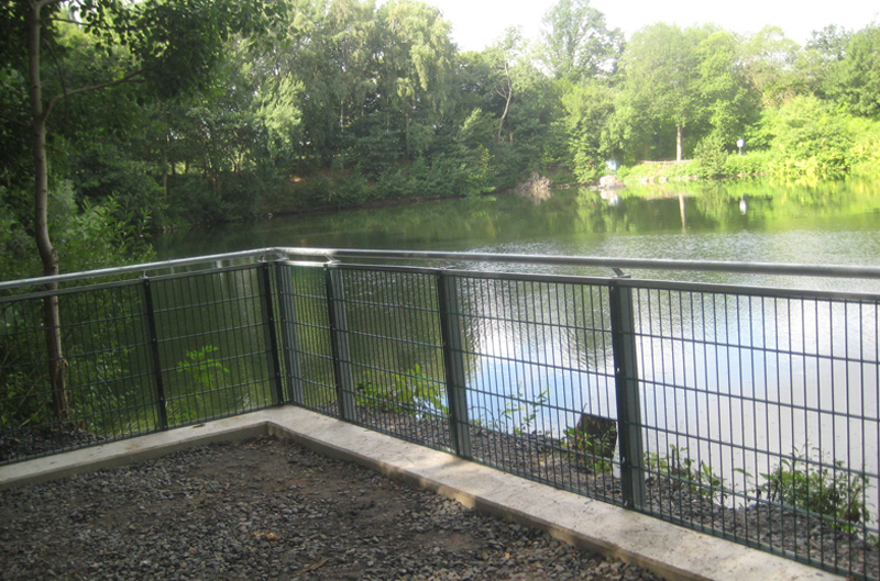 Aufnahme Metallzaun mit Fluss im Hintergrund